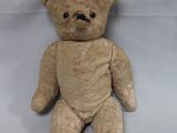 un ours en peluche marron assis sur un drap blanc