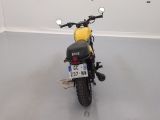 a yellow motorcycle parked in a room with a white wall