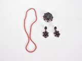 un collier, des boucles d'oreilles et un fil rouge sur un fond blanc
