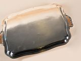 a silver tray with a handle on a white table