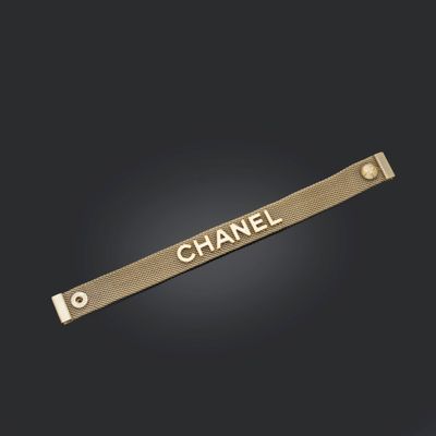 le mot « Chanel » inscrit sur une barre métallique dorée, sur fond noir