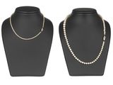 une paire de colliers de perles posés sur un présentoir pour mannequin