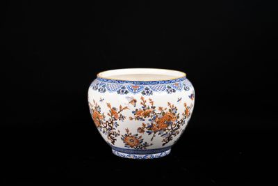 un vase blanc orné de fleurs orange sur fond noir