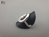 un gros plan d'une bague en argent posée sur un morceau de cuir noir
