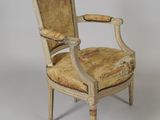 an old chair with a floral upholstered seat and arm rest