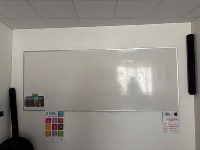 un tableau blanc accroché au mur, dans un coin de la pièce