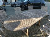 une table en bois entourée de six chaises, posée sur du gravier