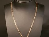 a gold necklace with a cross pendant on a mannequin