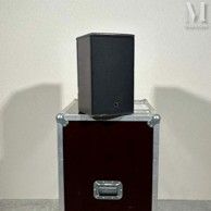 une enceinte noire posée sur une caisse en bois