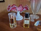bottles of perfume sitting on a wooden table next to a vase of flowers