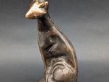 a bronze statue of a cat sitting on a black surface