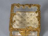 a gold box with a mirror on it on a table