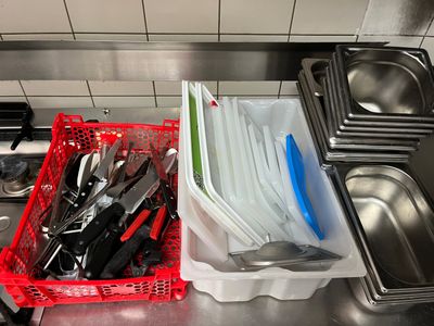 de nombreux ustensiles dans un panier rouge posé sur le plan de travail de la cuisine