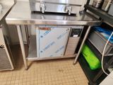 une cuisine équipée d'un plan de travail en inox et d'un réfrigérateur