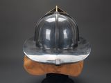 an old fireman ' s helmet on a wooden stand against a gray background
