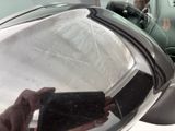 reflection of a person holding a cell phone in a car ' s rear view mirror
