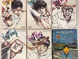 six albums de BD sont alignés sur une surface blanche