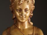 a gold statue of a woman with a flower in her hair