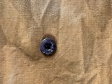 a blue button on a tan cloth with a brown background