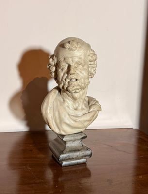 une statue représentant un homme barbu posée sur une table en bois