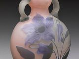 a vase with purple flowers painted on it on a gray surface