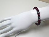 une main de mannequin blanche ornée d'un bracelet de perles rouges