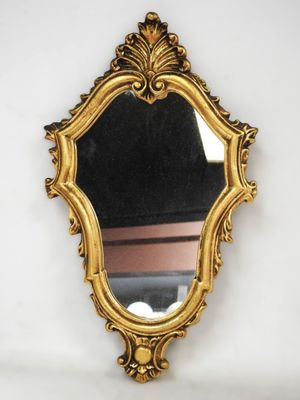 un miroir doré sur un mur blanc, avec un fond noir