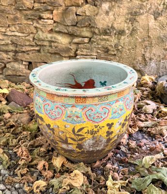 un vase coloré posé par terre près d'un mur de briques