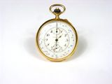 gros plan d'une montre de poche en or sur une surface blanche