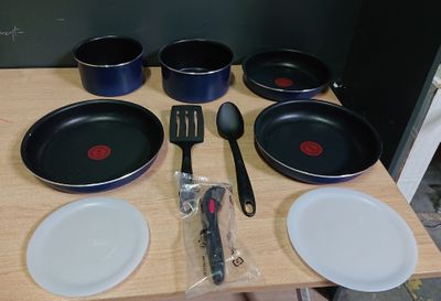 Plusieurs casseroles et ustensiles sont posés sur une table en bois