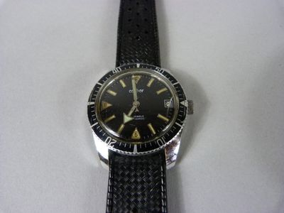 gros plan d'une montre sur une surface blanche avec un bracelet noir