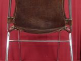 pair of brown leather folding chairs against a red backdrop