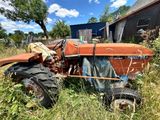 un tracteur qui est garé dans l'herbe à côté d'une grange