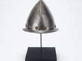 an antique helmet on a black stand on a white background