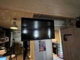 une télévision à écran plat fixée au-dessus d'un réfrigérateur dans une cuisine