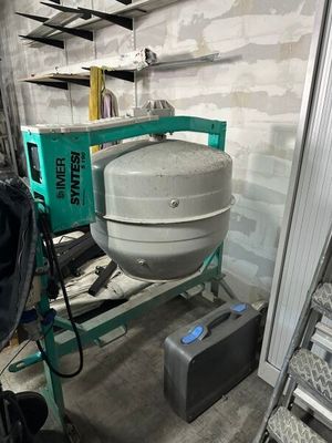 une bétonnière posée dans une pièce, avec une échelle à côté