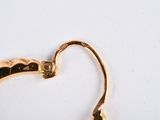 a close up of a pair of gold earrings on a white surface