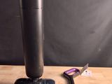 un aspirateur noir et argent posé sur une table à côté d'une brosse à dents