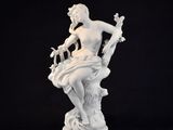 white statue of a woman sitting on a rock with a bird in her hand