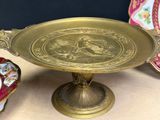 a gold plate with a bird on it on a table
