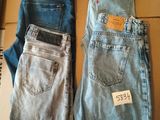 Deux paires de jeans sont posées sur une boîte en carton sur laquelle est accrochée une étiquette de prix.