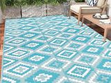 un tapis d'extérieur bleu et blanc posé sur une terrasse en bois