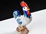 rooster figurine on a white surface with a black background