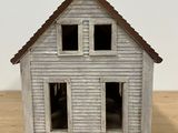 a small white house with two windows on a wooden table