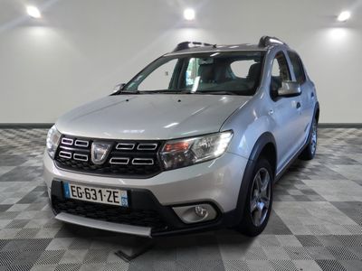 une photo d'une Dacia argentée garée sur un sol à damier