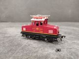 a small red train on the tracks on a gray surface