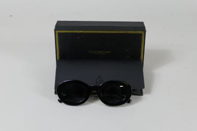 une paire de lunettes de soleil noires posée sur une table blanche