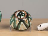 three ceramic objects on display on a wooden table
