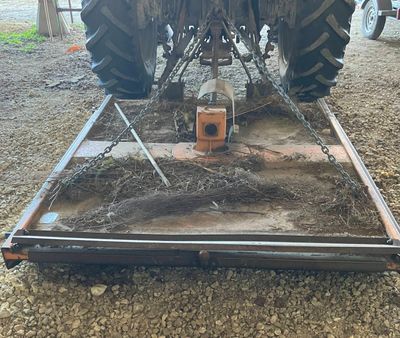 un tracteur garé sur une remorque, sur un terrain en terre battue