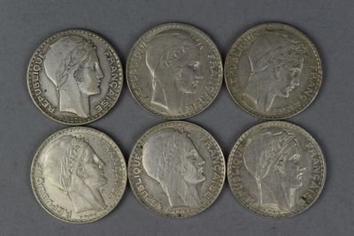 six silver coins of different sizes and shapes on a gray surface
